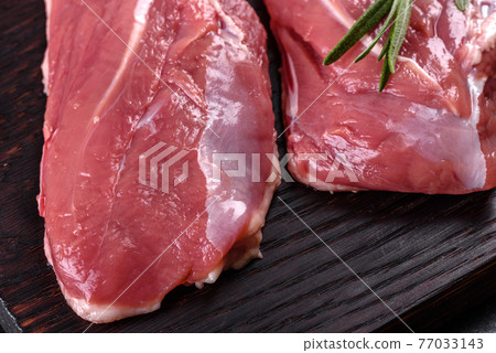 Raw duck breast with herbs and spices on a dark concrete background Raw duck breast with herbs and spices on a dark concrete background 77033143