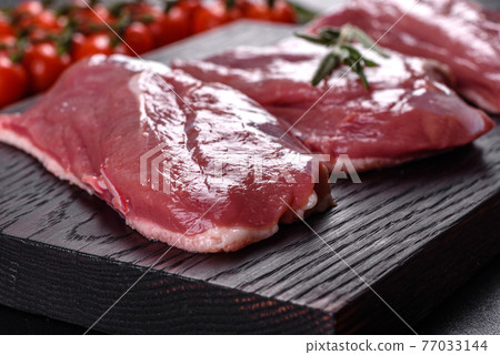 Raw duck breast with herbs and spices on a dark concrete background Raw duck breast with herbs and spices on a dark concrete background 77033144