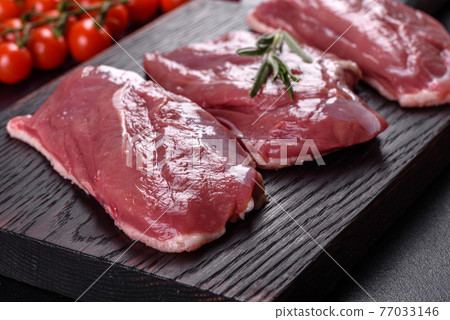 Raw duck breast with herbs and spices on a dark concrete background Raw duck breast with herbs and spices on a dark concrete background 77033146