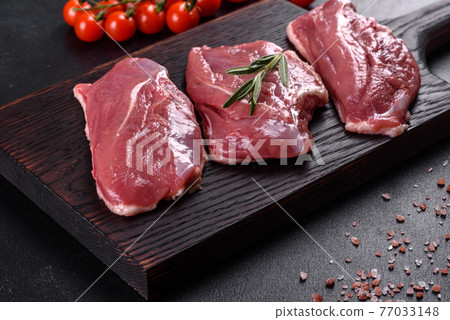 Raw duck breast with herbs and spices on a dark concrete background Raw duck breast with herbs and spices on a dark concrete background 77033148