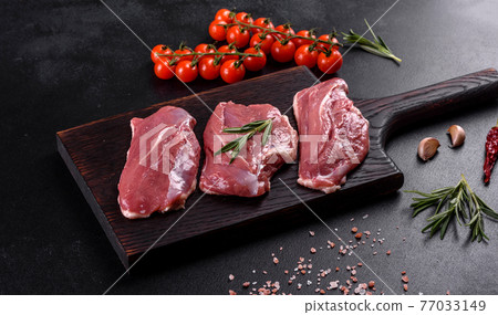Raw duck breast with herbs and spices on a dark concrete background Raw duck breast with herbs and spices on a dark concrete background 77033149