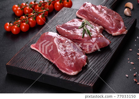 Raw duck breast with herbs and spices on a dark concrete background Raw duck breast with herbs and spices on a dark concrete background 77033150