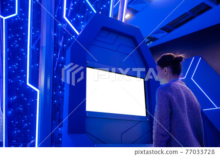 Woman looking at blank white display kiosk at exhibition - white screen concept Woman looking at blank white display kiosk at exhibition - white screen concept 77033728