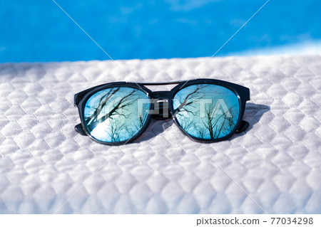 Fashion Sunglasses design with blue lenses shoot outside in a summer day closeup. Selective focus 77034298