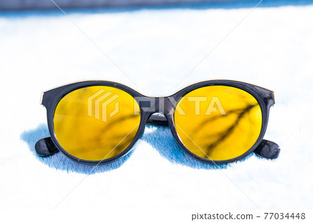 Fashion cat eye sunglasses for ladies with big round yellow lenses and black frame shoot outside in a sunny day closeup. Selective focus  77034448