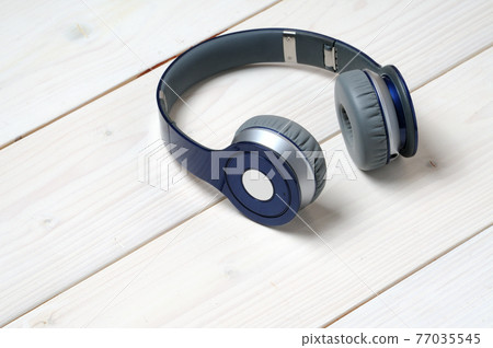 Blue and silver modern headphones on a white wooden background 77035545