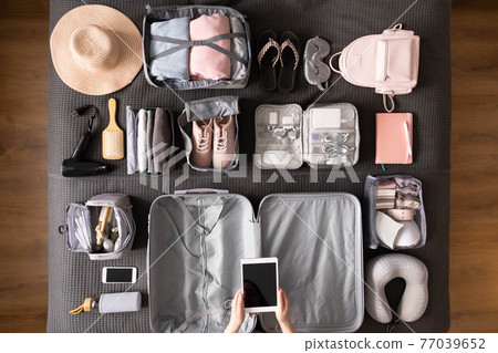 Top view woman hands getting ready to travel vacation packing suitcase use konmari method Top view woman hands getting ready to travel vacation packing suitcase use konmari method 77039652