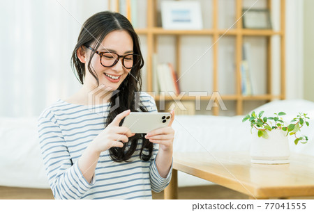A young woman watching a video on her smartphone A young woman watching a video on her smartphone 77041555