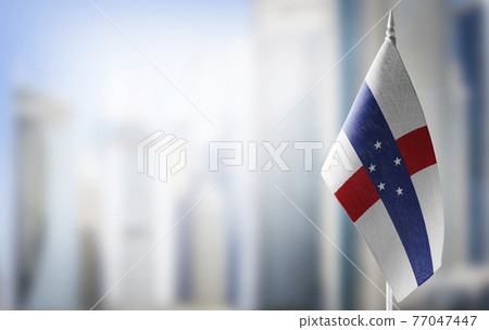 A small flag of Netherlands Antilles on the background of a blurred background A small flag of Netherlands Antilles on the background of a blurred background 77047447