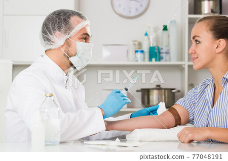 Male nurse injecting female patient 77048191