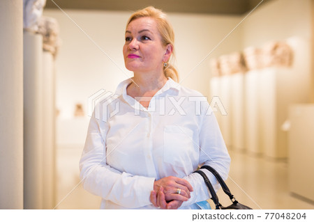 Portrait of senior woman visiting exposition at museum Portrait of senior woman visiting exposition at museum 77048204