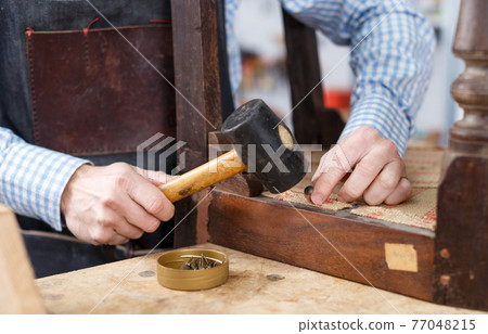 Hands working with hammer in workshop 77048215