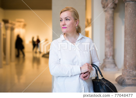 Portrait of senior woman visiting exposition at museum 77048477