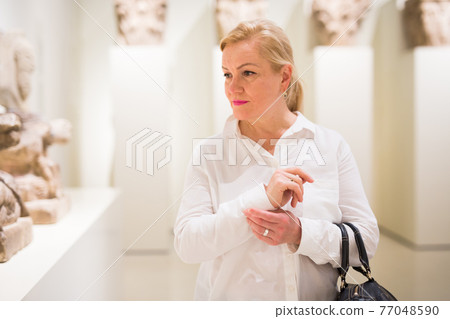 Portrait of senior woman visiting exposition at museum Portrait of senior woman visiting exposition at museum 77048590