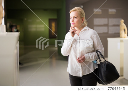Portrait of senior woman visiting exposition at museum Portrait of senior woman visiting exposition at museum 77048645