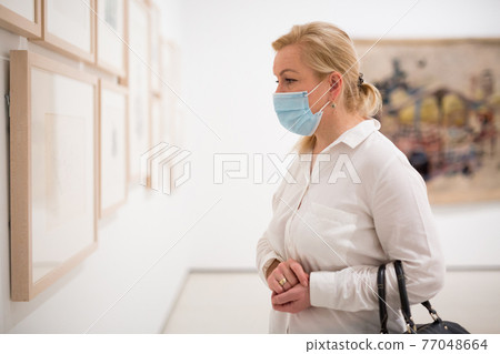 Closeup on mature female in face mask visiting museum 77048664