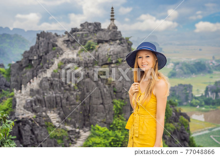 Woman tourist on top pagoda of Hang Mua temple, rice fields, Ninh Binh, Vietnam. Vietnam reopens borders after quarantine Coronovirus COVID 19 Woman tourist on top pagoda of Hang Mua temple, rice fields, Ninh Binh, Vietnam. Vietnam reopens borders after quarantine Coronovirus COVID 19 77048866