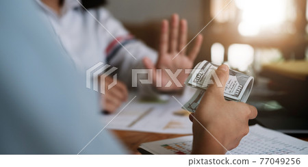 Businesswoman rejecting money in white envelope offered by his partner in the dark - anti bribery concept. Businesswoman rejecting money in white envelope offered by his partner in the dark - anti bribery concept. 77049256