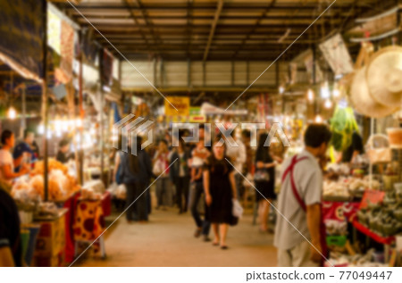 The image is blurred of people shopping in the market. The image is blurred of people shopping in the market. 77049447