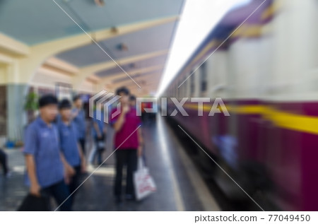 The image is blurred, the passengers are waiting to board the train at the station. The image is blurred, the passengers are waiting to board the train at the station. 77049450