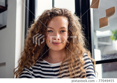 Portrait shot of happy pretty Caucasian woman smiling at the camera in living room at home Portrait shot of happy pretty Caucasian woman smiling at the camera in living room at home 77049455