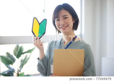 Female employee with beginner mark and binder Female employee with beginner mark and binder 77049479