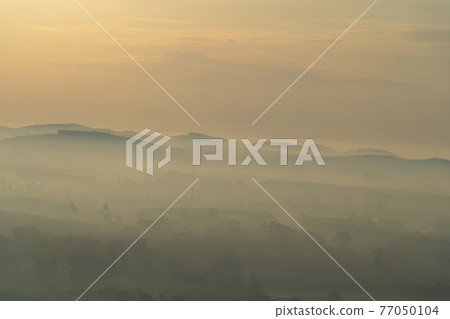 Aerial top view of forest trees with fog mist and green mountain hill at sunset. Nature landscape background, Thailand. Aerial top view of forest trees with fog mist and green mountain hill at sunset. Nature landscape background, Thailand. 77050104