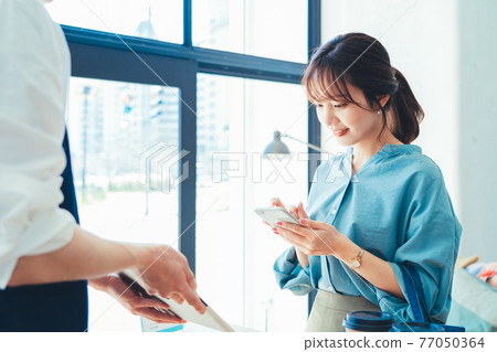 一位女士在收銀台結賬時準備用智能手機付款 77050364