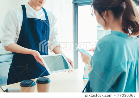 一位女士在收銀台結賬時準備用智能手機付款 77050365