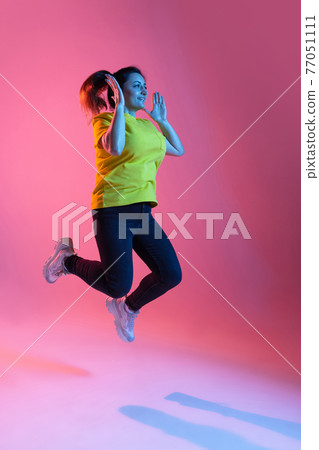 Portrait of beautiful happy woman isolated on pink background in neon light Portrait of beautiful happy woman isolated on pink background in neon light 77051111