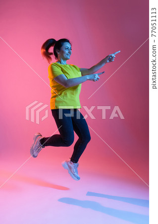 Portrait of beautiful happy woman isolated on pink background in neon light Portrait of beautiful happy woman isolated on pink background in neon light 77051113