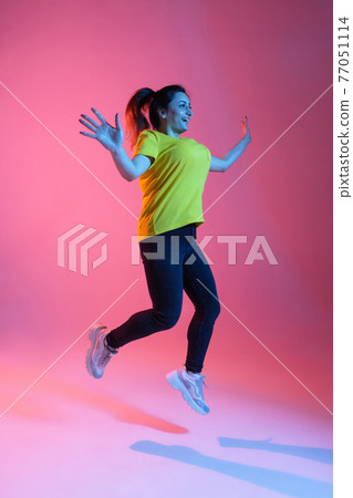 Portrait of beautiful happy woman isolated on pink background in neon light Portrait of beautiful happy woman isolated on pink background in neon light 77051114