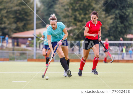 Two field hockey female players struggle for ball Two field hockey female players struggle for ball 77052438