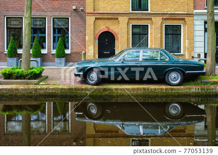 Old car on canal embankment in street of Delft. Delft, Netherlands 77053139