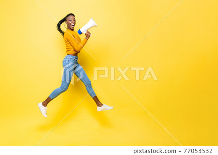 Jumping portrait of ecstatic smiling young African American woman with megaphone with copy space Jumping portrait of ecstatic smiling young African American woman with megaphone with copy space 77053532
