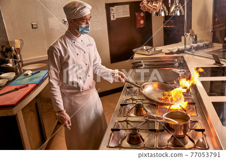 Burning vegetables on fire lying in frying pan Burning vegetables on fire lying in frying pan 77053791