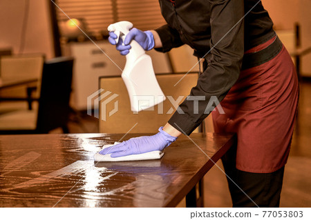 Restaurant worker washing a sprayed table with cloth Restaurant worker washing a sprayed table with cloth 77053803