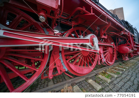 Close-up of the heavy iron wheels of a historic locomotive. 77054191