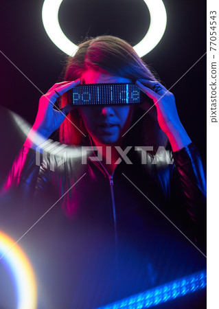 Cyberpunk style portrait of beautiful young woman in futuristic costume. 77054543