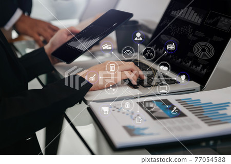 Business documents on office table with smart phone, tablet and laptop computer and graph with social network diagram and two colleagues discussing data in office. Business documents on office table with smart phone, tablet and laptop computer and graph with social network diagram and two colleagues discussing data in office. 77054588