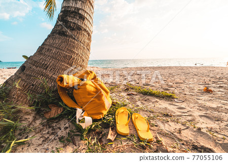 Sea vacation - Yellow Bags and Flip flops on the beach in the evening 77055106