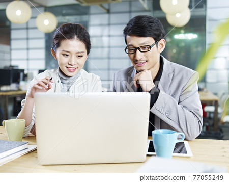 young asian business people sitting at desk working together using laptop computer young asian business people sitting at desk working together using laptop computer 77055249