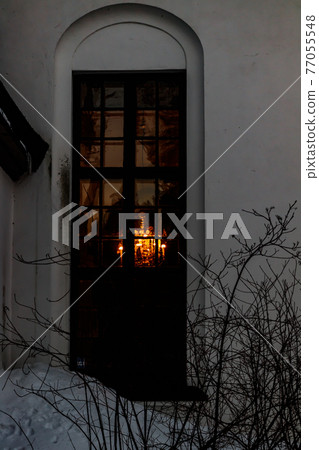 Beautiful chandelier light through the window of church of Valkeala in winter evening. 77055548