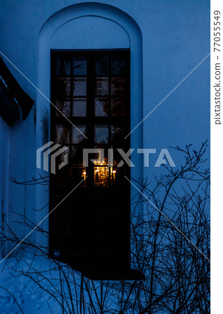 Beautiful chandelier light through the window of church of Valkeala in winter evening. 77055549