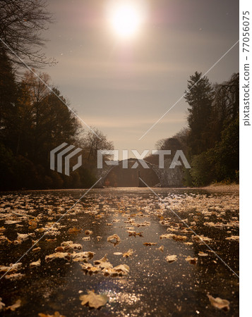 Full moon light on frozen lake with colorful leaves, round Rakotzbruecke Full moon light on frozen lake with colorful leaves, round Rakotzbruecke 77056075