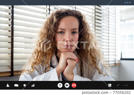 Serious female doctor carefully listening and hand under chin while making medical video call Serious female doctor carefully listening and hand under chin while making medical video call 77056202