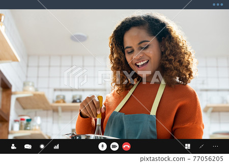 Happy smiling young African American woman making video call while cooking in kitchen at home 77056205