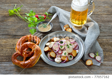Bavarian beer garden snack with veal sausage salad and pretzels, served with a mug of lager beer 77057162
