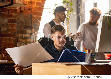 Colleagues working together in modern office using devices and gadgets during creative meeting 77057359