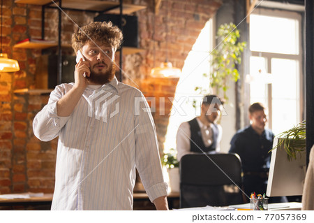 Colleagues working together in modern office using devices and gadgets during creative meeting 77057369